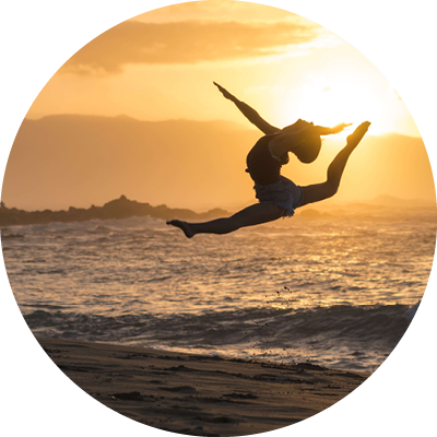 Silhouette of an acrobat leaping in the air at sunset by the beach representing flexibility
